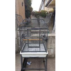 Black metal birdcage on stand with shelf